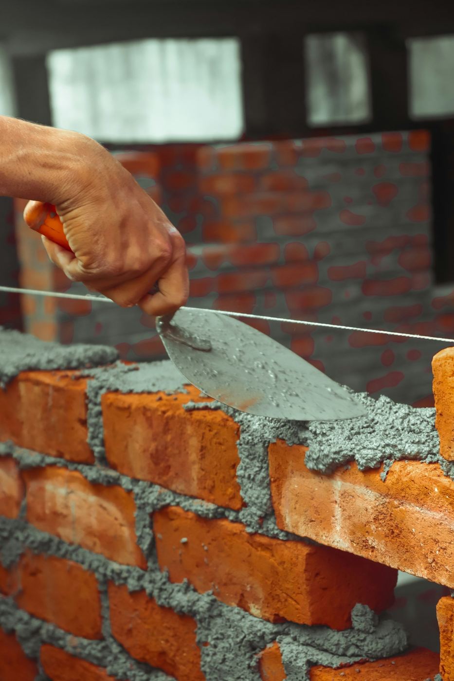 Truelle appliquant du mortier sur un mur de briques en construction